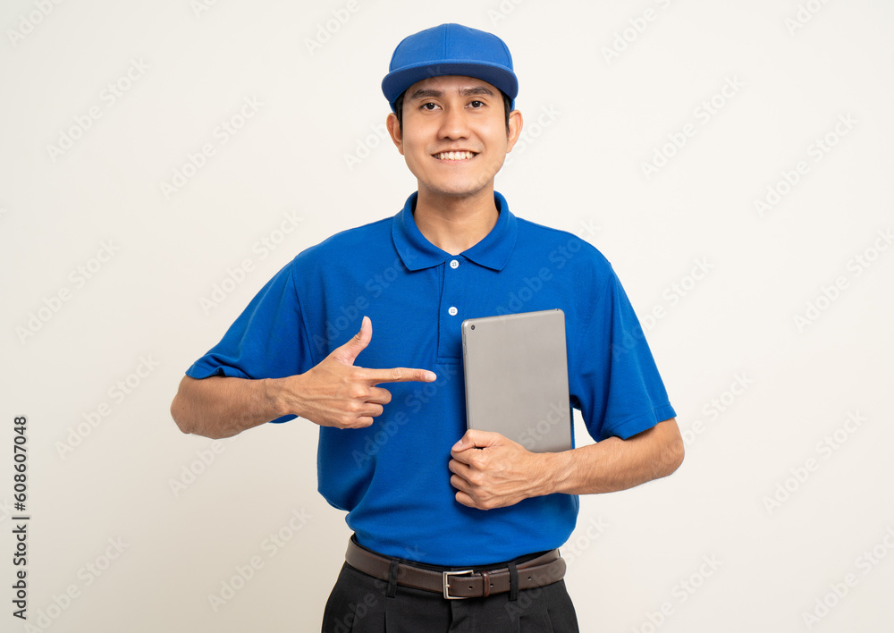 Asian man in blue uniform standing holding digital tablet computer on isolated white background. Male service worker with cell phone. Delivery courier shipping service Asian man in blue uniform standing holding digital tablet computer on isolated white background. Male service worker with cell phone. Delivery courier shipping service