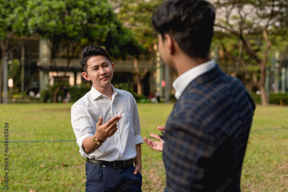 A young asian man has a casual conversation with an old friend after a chance encounter outside the office. A young asian man has a casual conversation with an old friend after a chance encounter outside the office.