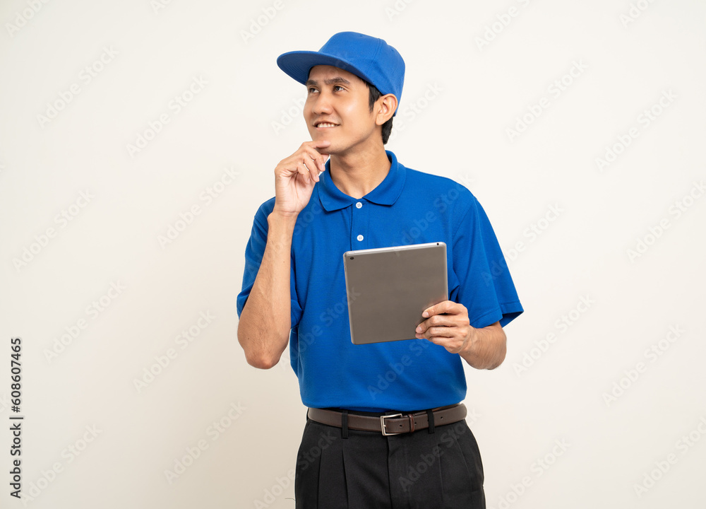 Asian man in blue uniform standing holding digital tablet computer on isolated white background. Male service worker with cell phone. Delivery courier shipping service Asian man in blue uniform standing holding digital tablet computer on isolated white background. Male service worker with cell phone. Delivery courier shipping service