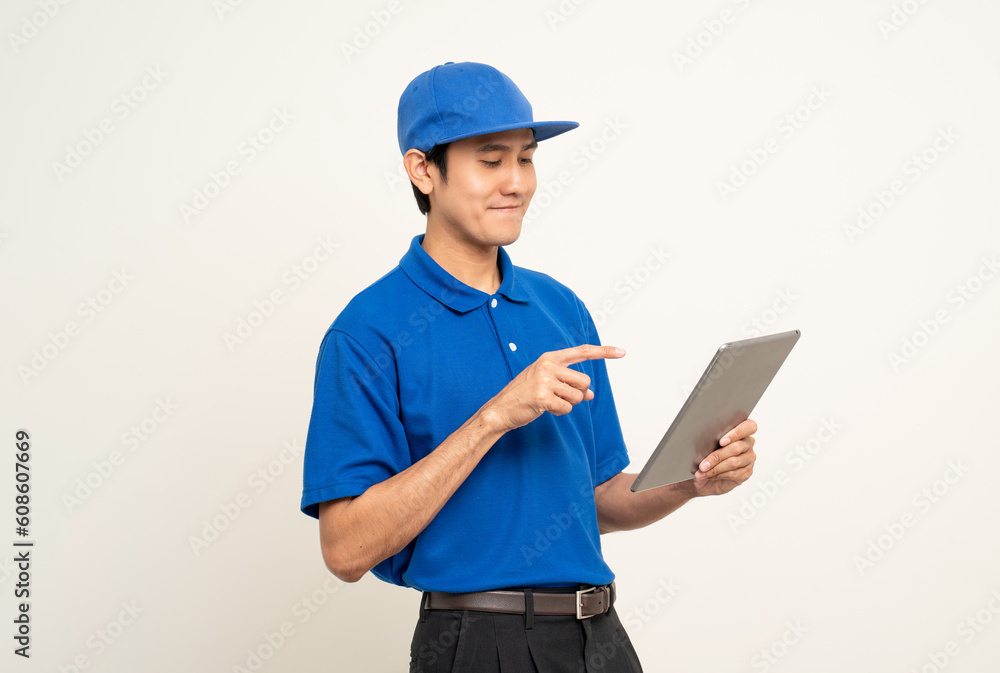 Asian man in blue uniform standing holding digital tablet computer on isolated white background. Male service worker with cell phone. Delivery courier shipping service Asian man in blue uniform standing holding digital tablet computer on isolated white background. Male service worker with cell phone. Delivery courier shipping service
