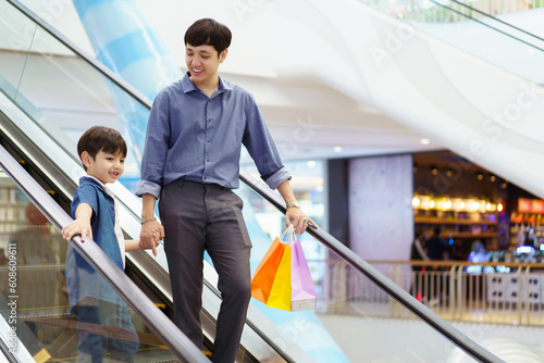 Happy cheerful man and little son walking in the supermarket or department store together. Asian man bought a gifts and toys for his son at department store.