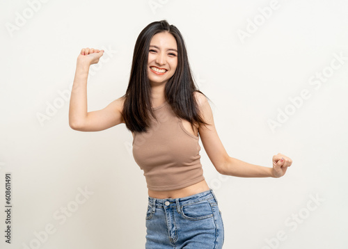 Cheerful cute asian female teenager listen to the music and dancing on isolated white background. Happy Beautiful pretty young woman in brown shirt having fun with the music in room.