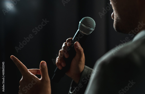 Quadro em tela Confident successful speaker man talking on stage with spotlight strike through the darkness at corporate business event
