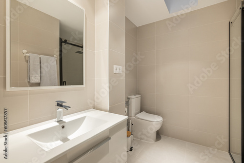Stylish spacious bathroom with toilet  shower and sink with cabinet and mirror in beige tones in a new building. Concept of convenient and concise renovation in the bathroom. Copyspace