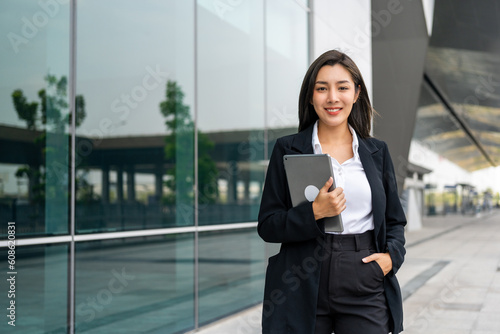 Portrait beautiful Businesswoman in suit with tablet standing at the buildings downtown. Confident woman using tablet. Executive Smart businessman