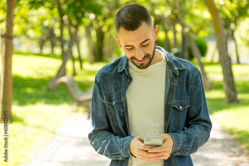 Young man texting while taking a walk in a park