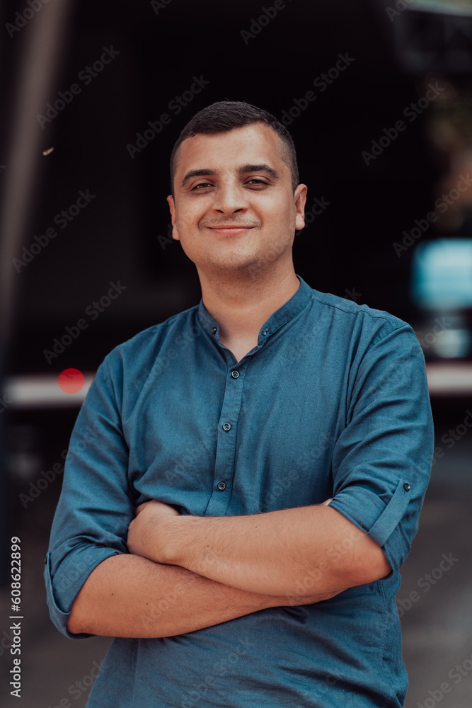 A successful young businessman in a shirt, with crossed arms, poses outdoors, confident expression on his face. A successful young businessman in a shirt, with crossed arms, poses outdoors, confident expression on his face.