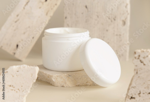 Opened white cream jar with a lid near biege stones close up. Cosmetic Mockup