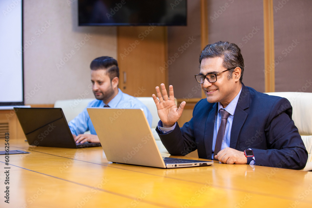 Indian businessman giving happy expression while looking in laptop Indian businessman giving happy expression while looking in laptop