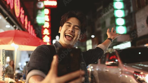 Traveler asian young man using smart phone camera to take photo, selfie or video call at china town in Bangkok. Backpacker travel on holiday trip or vacation concept
