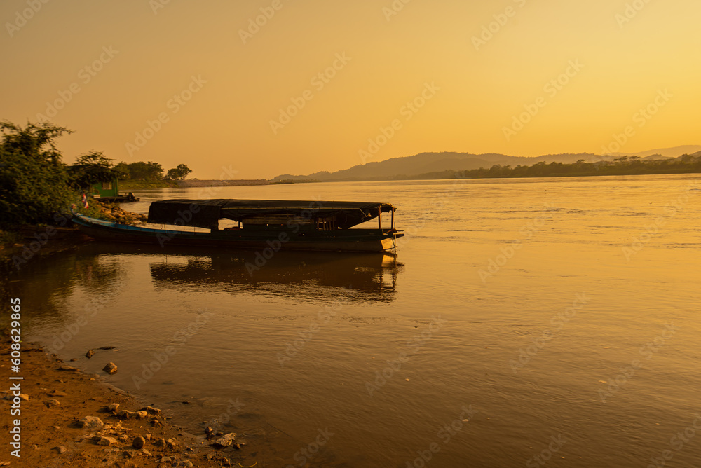 View of the morning Mekong River surrounded by mountains and yellow sunbeams in the sunset background at Chiang Khong, Chiang Rai, northern Thailand.
