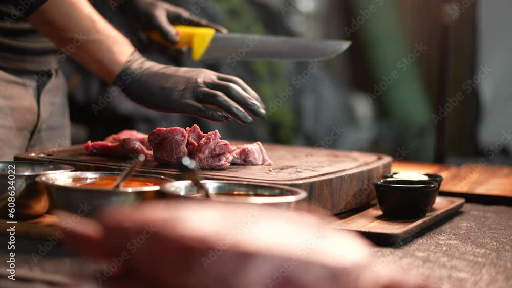 Professional cook cutting raw meat for barbecue Professional cook cutting raw meat for barbecue