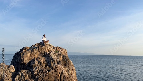 yoga man sitting on the evening sea cliff