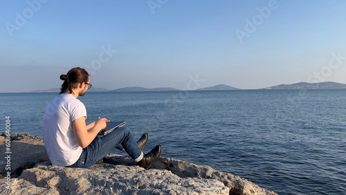 man sit near blue sea