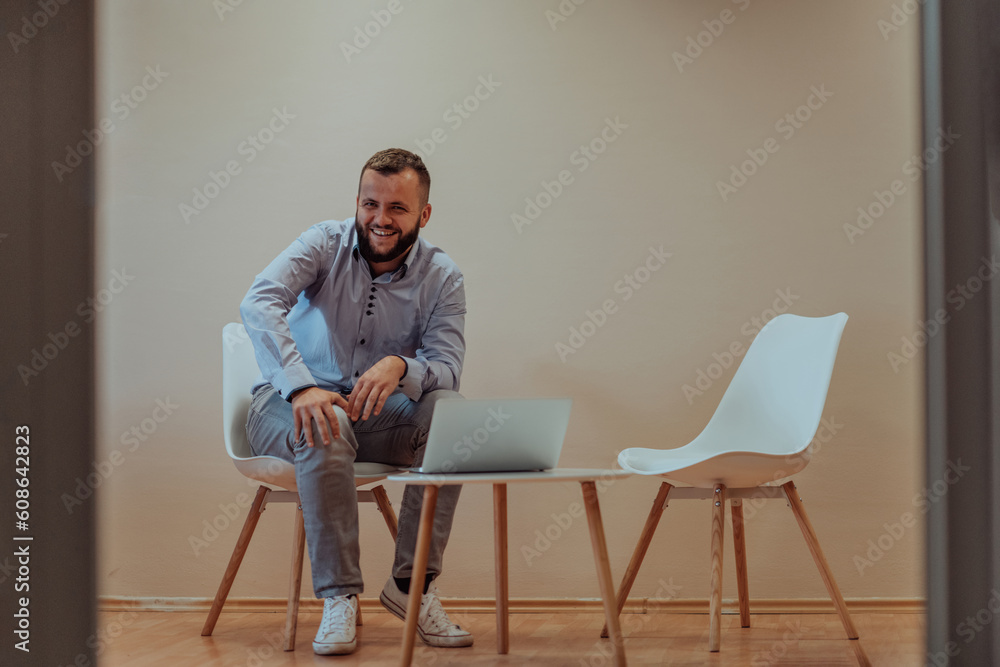 A confident businessman sitting and using laptop with a determined expression, while a beige background enhances the professional atmosphere, showcasing his productivity and expertise. A confident businessman sitting and using laptop with a determined expression, while a beige background enhances the professional atmosphere, showcasing his productivity and expertise.