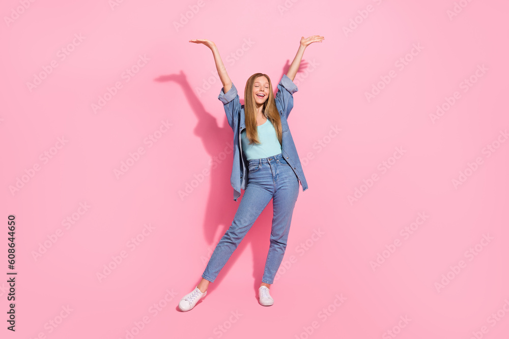 Full size photo of lovely young teenager lady raise hands celebrate excited wear trendy jeans garment isolated on pink color background Full size photo of lovely young teenager lady raise hands celebrate excited wear trendy jeans garment isolated on pink color background