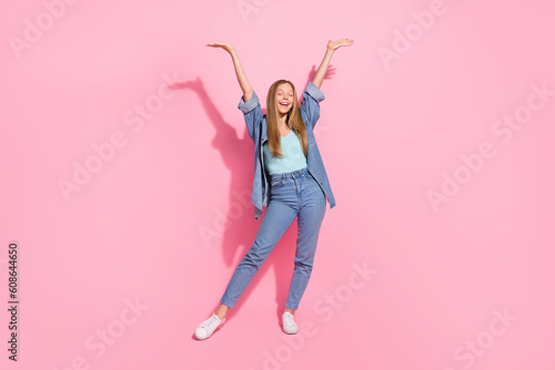 Full size photo of lovely young teenager lady raise hands celebrate excited wear trendy jeans garment isolated on pink color background
