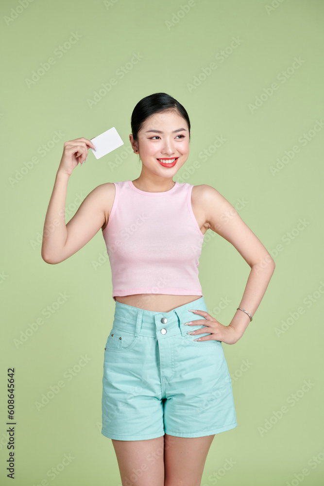 Beautiful young woman holding blank credit card against green background Beautiful young woman holding blank credit card against green background