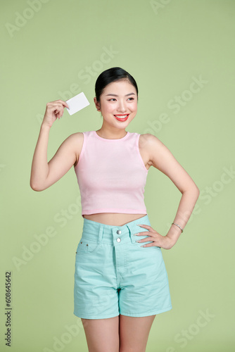 Beautiful young woman holding blank credit card against green background © makistock