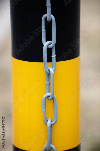 Security metal chain on black and yellow post © Tina Jenner