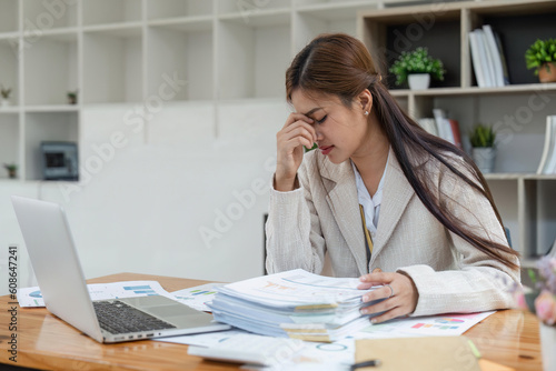 Business women are stressed while working on laptop and pile of documents, Tired businesswoman with headache at office, feeling sick at work