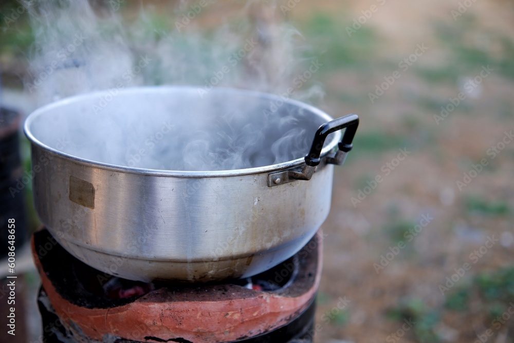 Hot boiling water in a pot with smoke on a Thai brazier,outdoor cooking Hot boiling water in a pot with smoke on a Thai brazier,outdoor cooking
