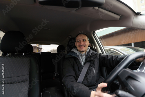 Man of style and status. Handsome young man in full suit smiling while driving a car © Angelov