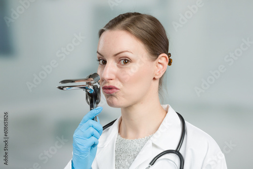 Female gynecologist makes funny gestures with a speculum to take away the fear