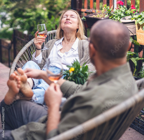 Happy middle aged caucasian couple enjoying a summer day drinking wine on the terrace of a country house. Summer lifestyle portrait