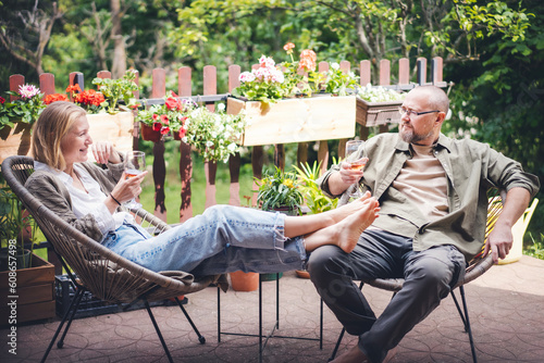 Happy middle aged caucasian couple enjoying a summer day drinking wine on the terrace of a country house. Summer lifestyle portrait