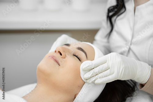 The first steps to perfection: the beautician prepares the skin of a woman's face for cosmetic procedures with cotton pads, cleansing and raising skin health.