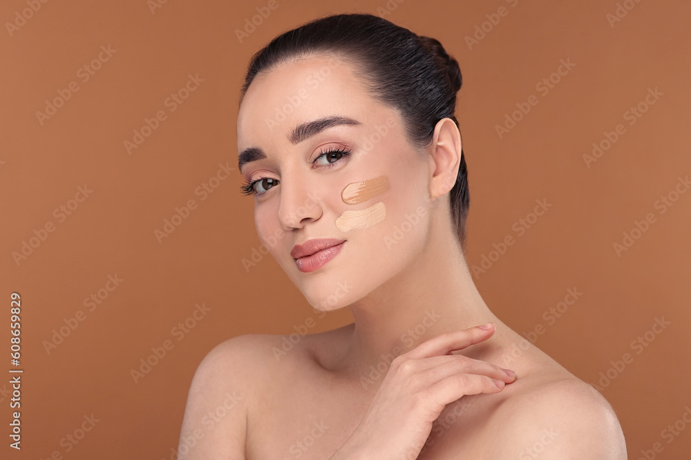 Woman with swatches of foundation on face against brown background Woman with swatches of foundation on face against brown background