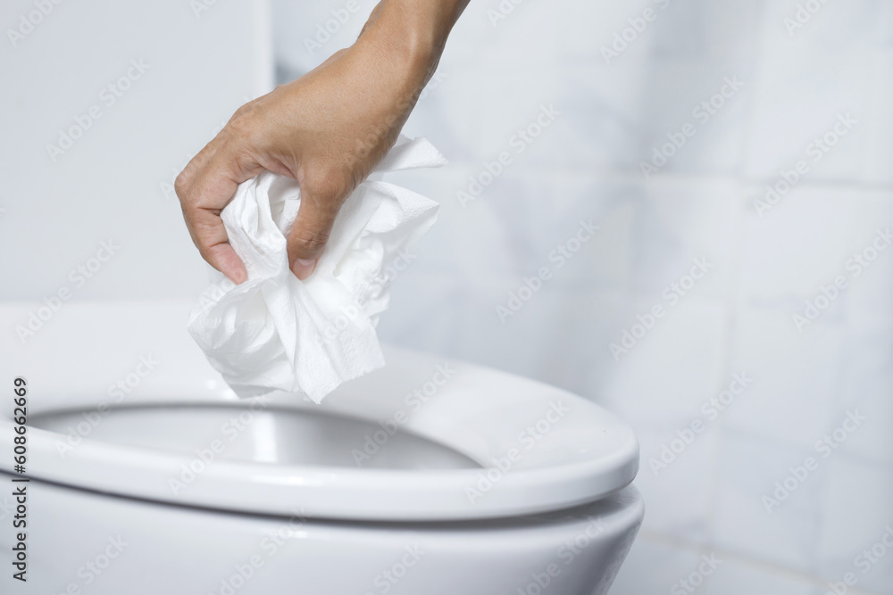 close up hand holding a tissue to be thrown into the toilet bowl. Can not drain water of toilet