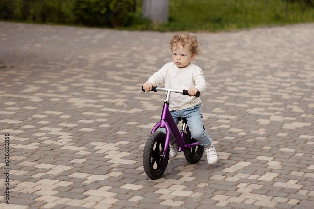 Cute little smiling child learning to ride a balance bike in the park Cute little smiling child learning to ride a balance bike in the park
