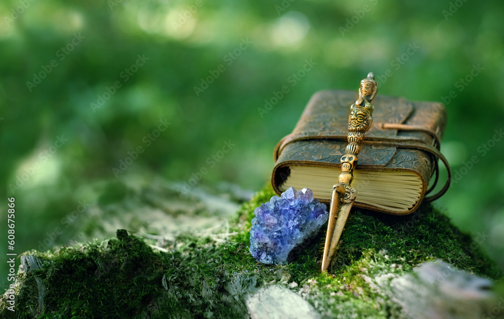 Ritual knife, amethyst druse, magic spell book on mossy stump, blurred natural green background. Phurba is three-sided knife, traditionally of Indo-Tibetan Buddhism for esoteric spiritual practice Ritual knife, amethyst druse, magic spell book on mossy stump, blurred natural green background. Phurba is three-sided knife, traditionally of Indo-Tibetan Buddhism for esoteric spiritual practice