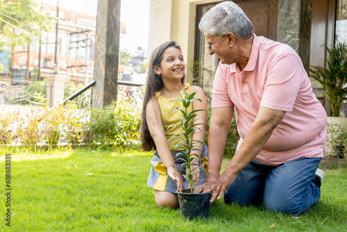 Grandfather gardening and teaching granddaughter take care plant indoors