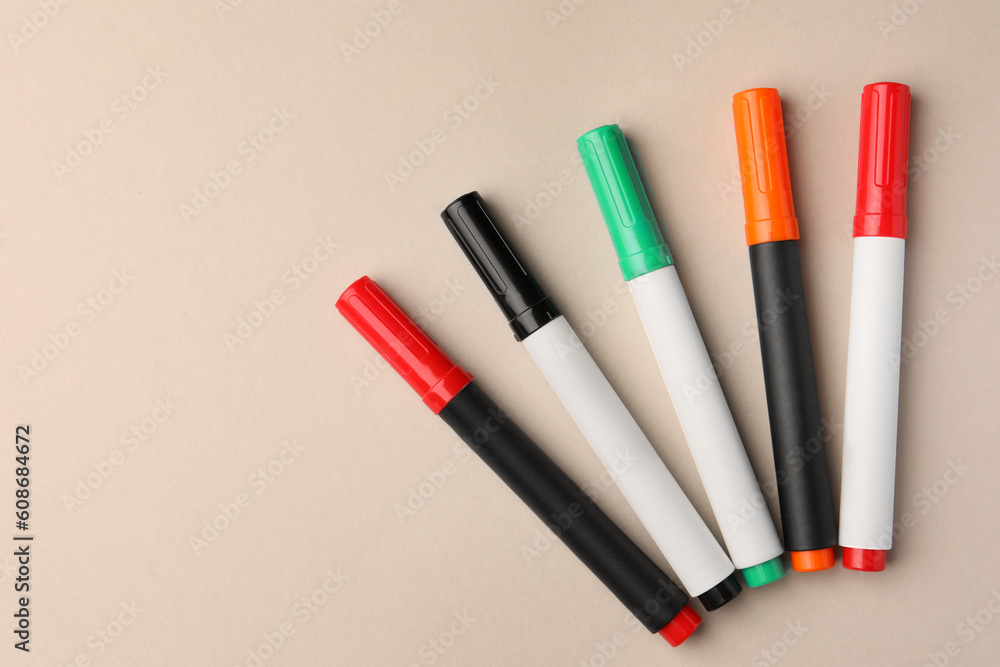 Bright color markers on beige background, flat lay. Space for text