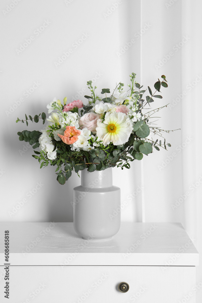 Bouquet with beautiful flowers on white chest of drawers indoors