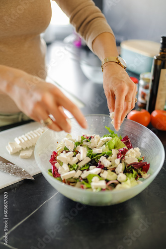 Young woman making salad in the kitchen at home. Healthy eating, dieting and people concept.