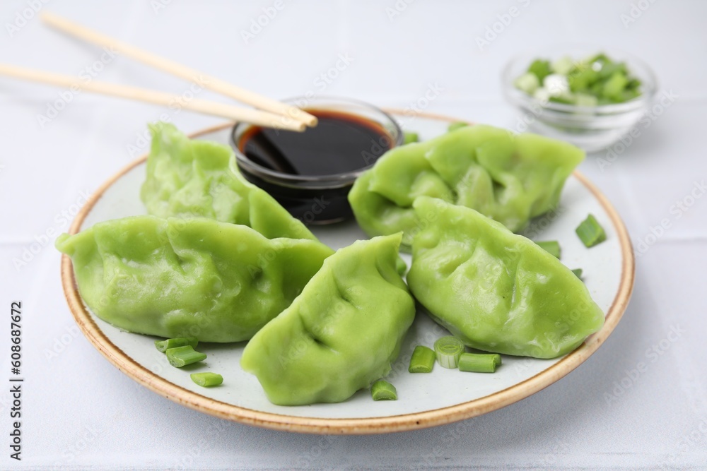 Delicious green dumplings (gyozas) with soy sauce served on white tiled table, closeup Delicious green dumplings (gyozas) with soy sauce served on white tiled table, closeup