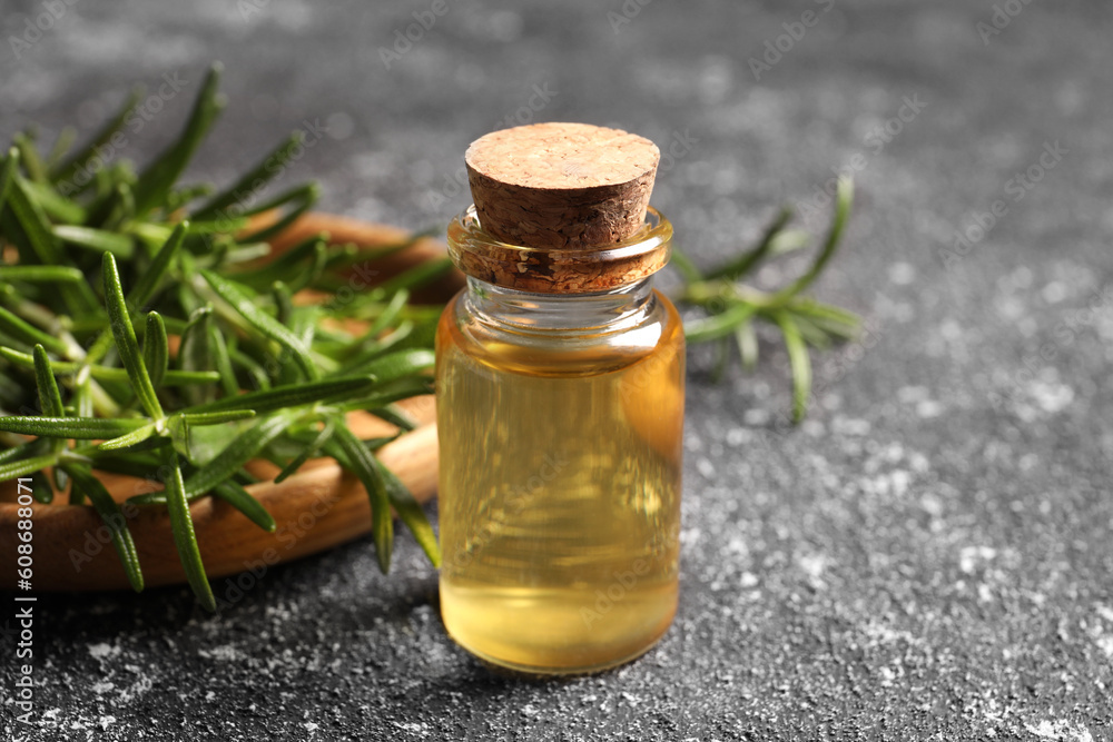 Bottle with oil and fresh rosemary on grey textured table, closeup Bottle with oil and fresh rosemary on grey textured table, closeup
