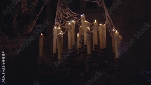 This video shows an old, antique candelabra covered with cobwebs and flickering to illuminate a dark rom.