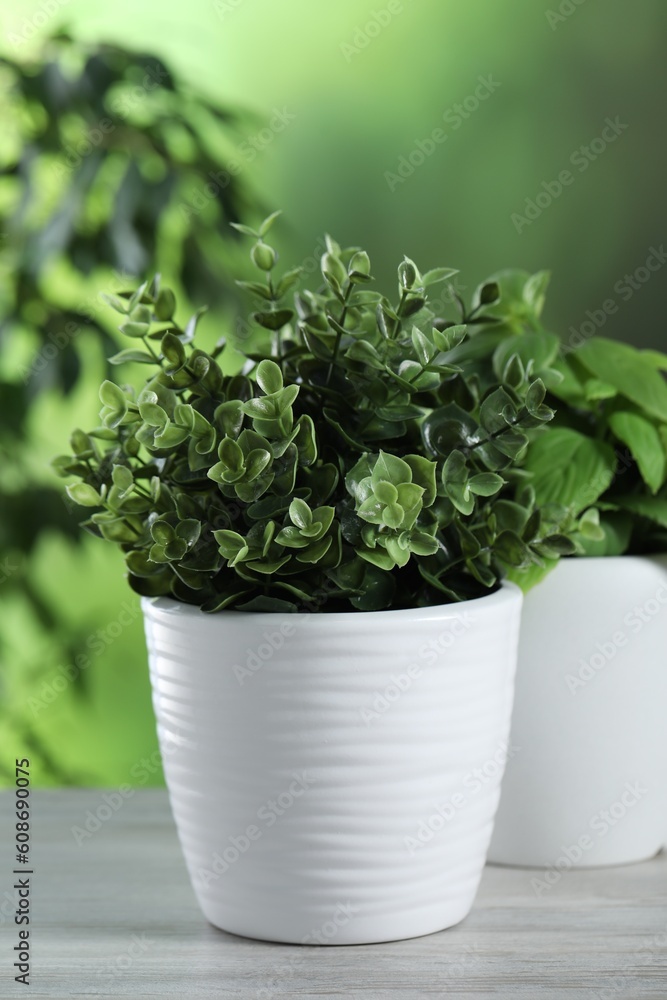 Fototapeta premium Different artificial potted herbs on white wooden table outdoors