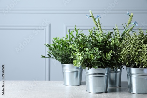 Different artificial potted herbs on light table, space for text © New Africa