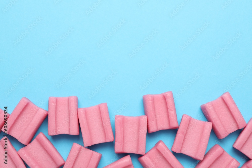 Tasty pink chewing gums on light blue background, flat lay. Space for text Tasty pink chewing gums on light blue background, flat lay. Space for text
