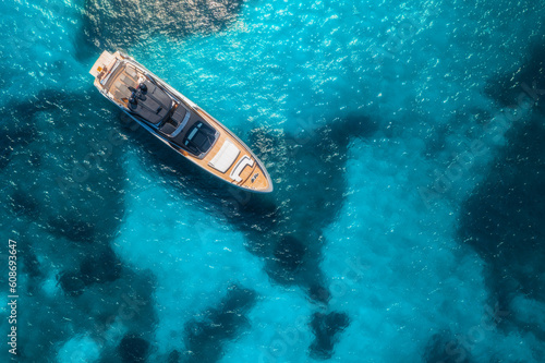 Aerial view of luxury yacht on blue sea at sunset in summer. Travel and yachting in Sardinia, Italy. Drone view from above of speed boat, sea lagoon, transparent azure water. Seascape. Vacation © den-belitsky