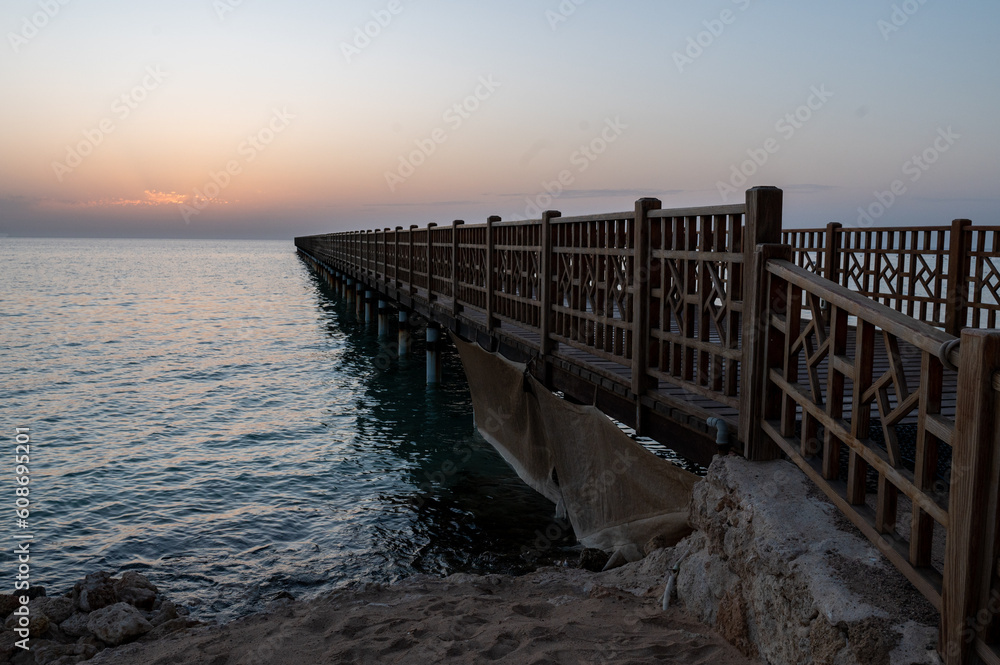 Obraz premium Beginning of a day, orange sunrise over the sea and pier, morning hours, sunset, beautiful romantic atmosphere.