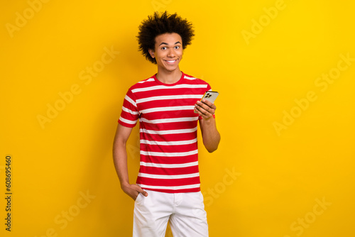 Portrait of positive nice man hold smart phone toothy smile isolated on yellow color background