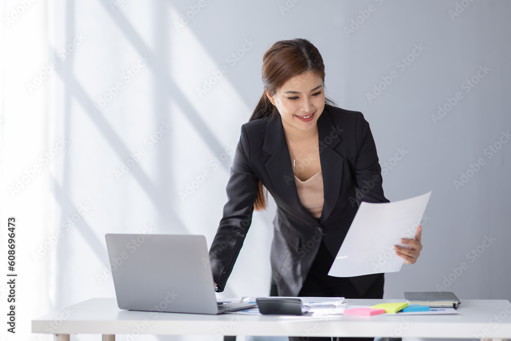 Asian student business woman using calculator and laptop for doing math finance on an office desk, tax, report, accounting, statistics, and analytical research concept Asian student business woman using calculator and laptop for doing math finance on an office desk, tax, report, accounting, statistics, and analytical research concept