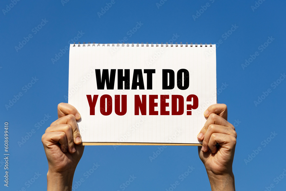 What do you need question text on notebook paper held by 2 hands with isolated blue sky background. This message can be used as business concept about what do you need. What do you need question text on notebook paper held by 2 hands with isolated blue sky background. This message can be used as business concept about what do you need.